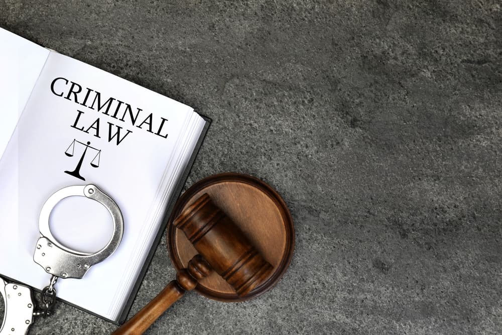 Book Criminal Law, judge's gavel and handcuffs on grey table