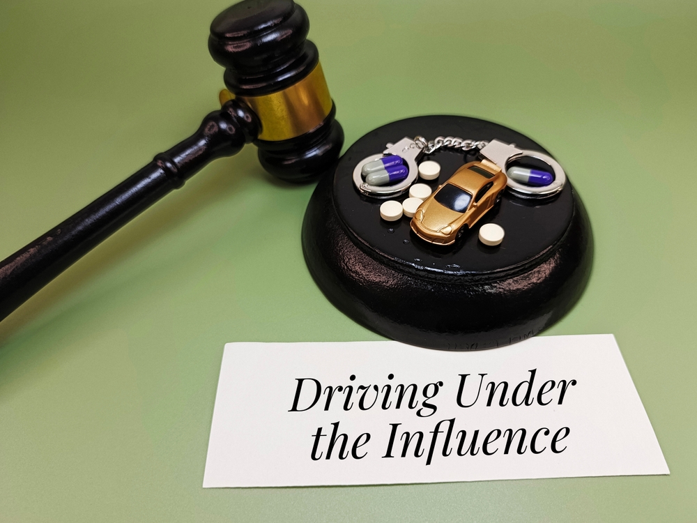 Judge&rsquo;s gavel with toy car, pills, and handcuffs symbolizing DUI cases in Georgia law.