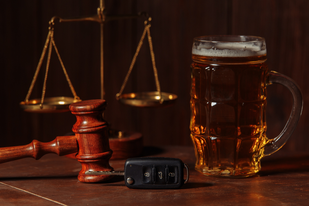 A judge’s gavel, a glass of beer, and car keys symbolizing DUI charges in Georgia