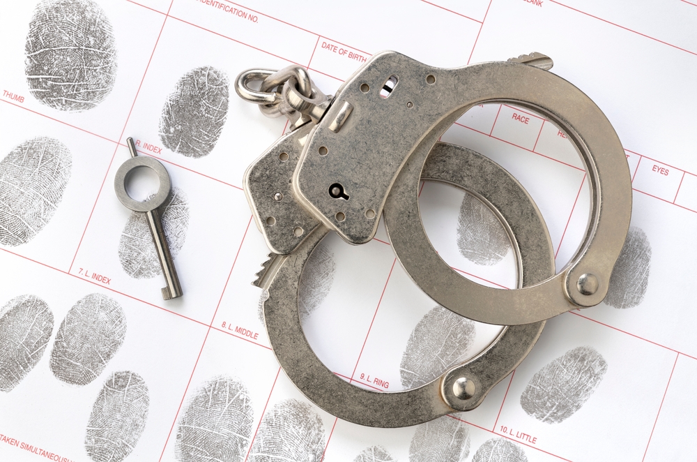 Handcuffs and a key placed on a fingerprint card during arrest processing